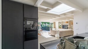 Eine moderne Küche mit Einbauofen, ein Essbereich mit Tisch und Stühlen sowie Blick ins Freie.