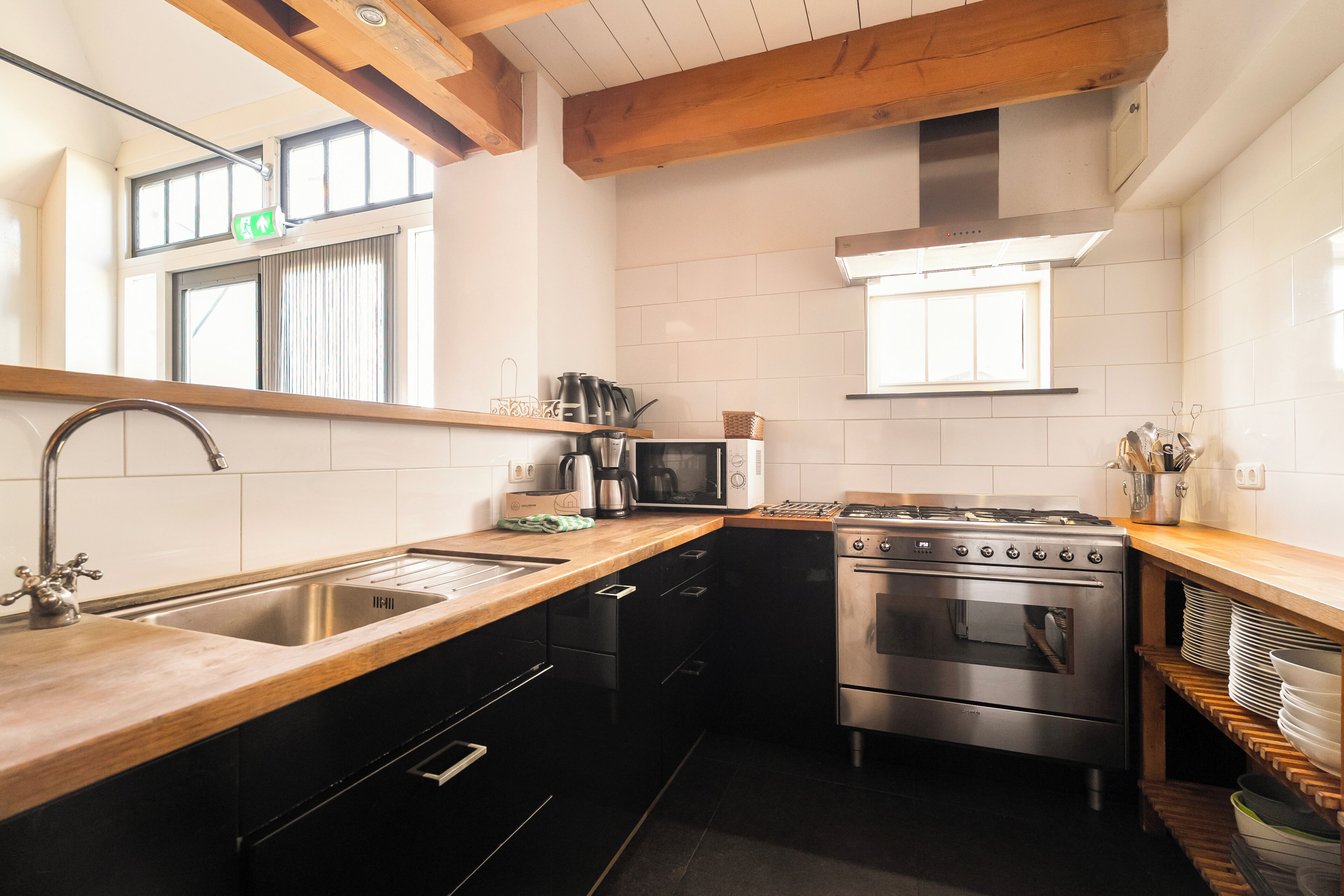 A modern kitchen with a stainless steel sink, a microwave, a stove, and black cabinets.