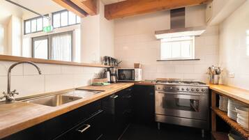 A modern kitchen with a stainless steel sink, a microwave, a stove, and black cabinets.