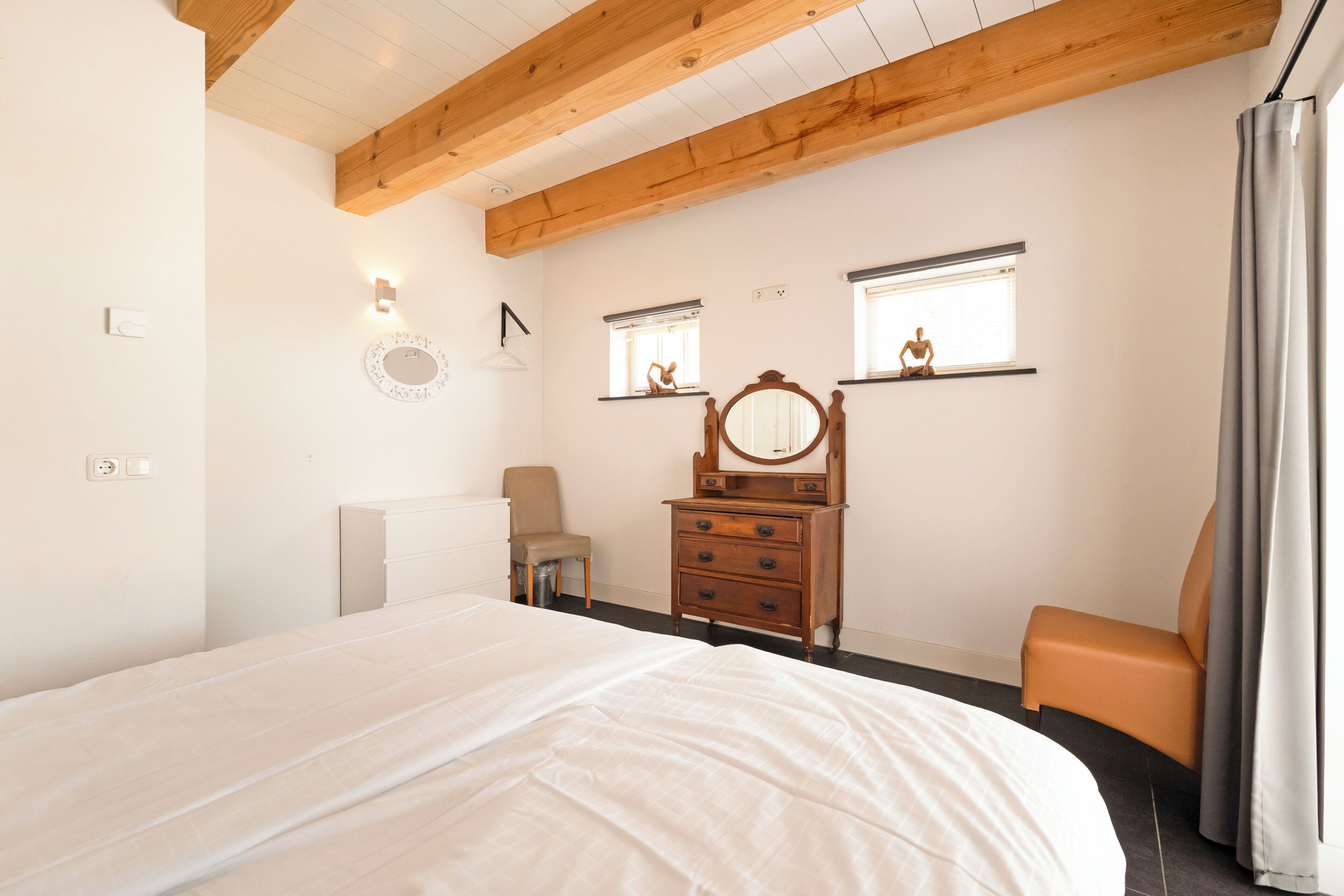 A bedroom with a bed, a dresser, a chair, and a window with a view.