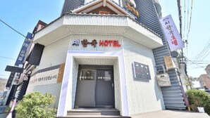 Entrada de hotel com uma placa indicando 'AI Hotel' e uma pequena placa acima da porta com a inscrição 'Proibido Fumar'.