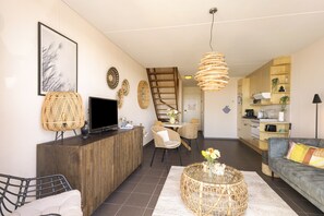 Ein modernes Wohnzimmer mit Sofa, Couchtisch, Fernseher und einem Essbereich mit Stühlen und Tisch.