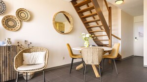 A modern interior with wicker furniture, a spiral staircase, and decorative woven plates on the wall. - A modernly furnished vacation rental with a view of the dunes of Groote Keeten. (Callantsoog)