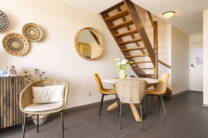 Ein modernes Interieur mit Korbmöbeln, einer Wendeltreppe und dekorativen Wandplatten aus Bändern.