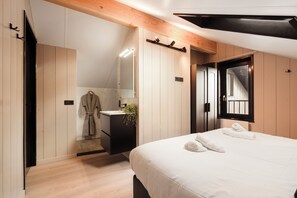 A modern bedroom with a large bed, a built-in desk, a mirror, and a window. - Zand Vacation Home – Luxury, Peace, and Space on the Coast (Julianadorp)