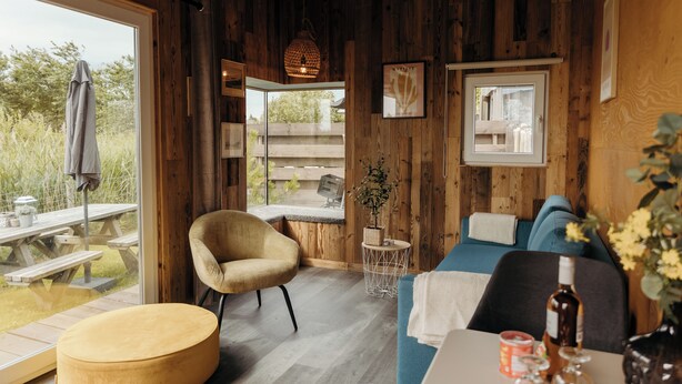 A cozy cabin interior with a wooden interior, a dining area with a table and chairs, and a view of the outdoors. - Unique accommodation (Callantsoog)