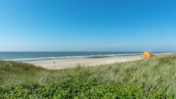 Een strand met een uitkijktoren voor de badwacht, grasduinen en de oceaan.