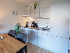 A modern kitchen with white cabinets, a coffee maker, and a sink.