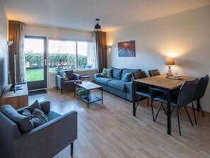 A modern living room with a sofa, coffee table, dining table, and chairs.