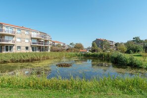 A residential area with a pond, multi-story buildings, and a clear sky. - Beautiful vacation rental for 4 people across from the wide dunes of Julianadorp aan Zee! (Julianadorp aan Zee)