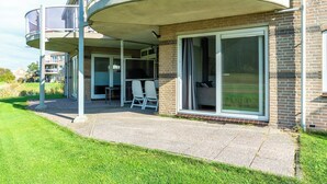 Ein Wohngebäude mit überdachter Terrasse, einer Schiebetür und einer Ziegelaußenwand.