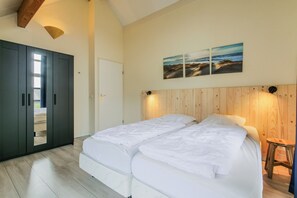 Ein Schlafzimmer mit Doppelbett, Holz-Kopfteil und Blick ins Freie.