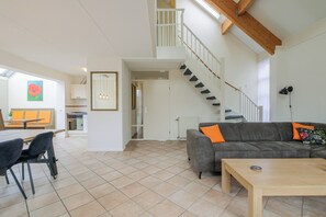 Ein großzügiger Wohnbereich mit Treppe, Esstisch und einer Couch.