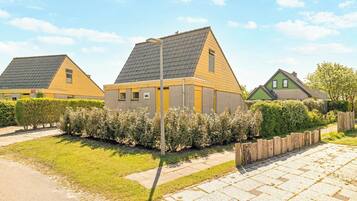 A row of modern houses with sloped roofs, a paved driveway, and a wooden fence.