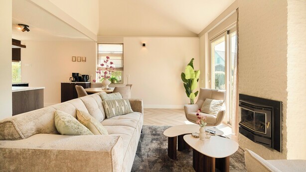 A modern living room with a sofa, armchairs, a fireplace, and a dining area. - This beautiful detached vacation home in Julianadorp aan Zee is fully equipped with all modern conveniences. (Julianadorp)