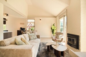 Ein modernes Wohnzimmer mit einer Couch, Sesseln, einem Kamin und einem Essbereich.