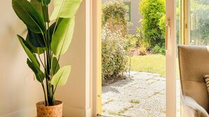 A room with a sliding glass door leading to a garden, a potted plant, and a chair. - This beautiful detached vacation home in Julianadorp aan Zee is fully equipped with all modern conveniences. (Julianadorp)