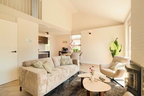 Ein Wohnzimmer mit einer Couch, einem Sessel, einem runden Couchtisch und einem Kamin.