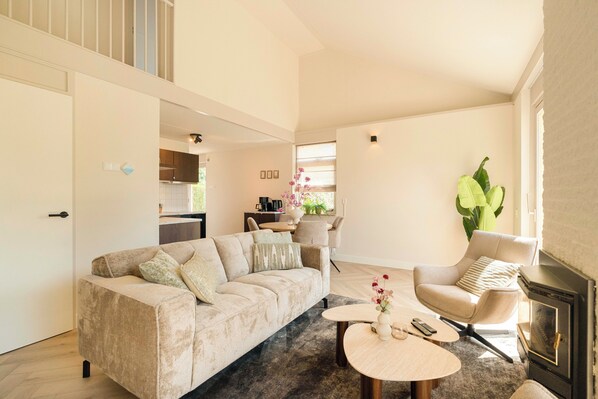 Ein Wohnzimmer mit einer Couch, einem Sessel, einem runden Couchtisch und einem Kamin.