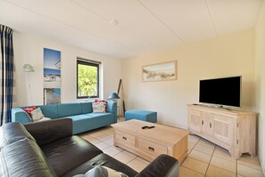 Ein modernes Wohnzimmer mit einer Couch, einem Couchtisch, einem Fernseher und einem Schrank.