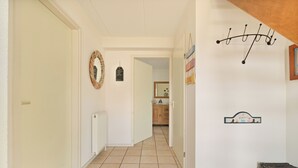 Ein Korridor mit Heizkörper, Tür und Spiegel an der Wand.