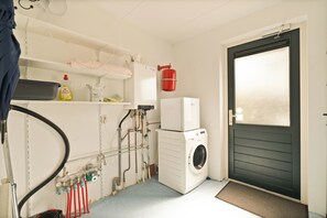 Ein Waschraum mit Waschmaschine, Trockner und verschiedenen Sanitärrohren.