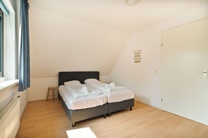 A bedroom with a bed, a small stool, a door, and a wall sign.