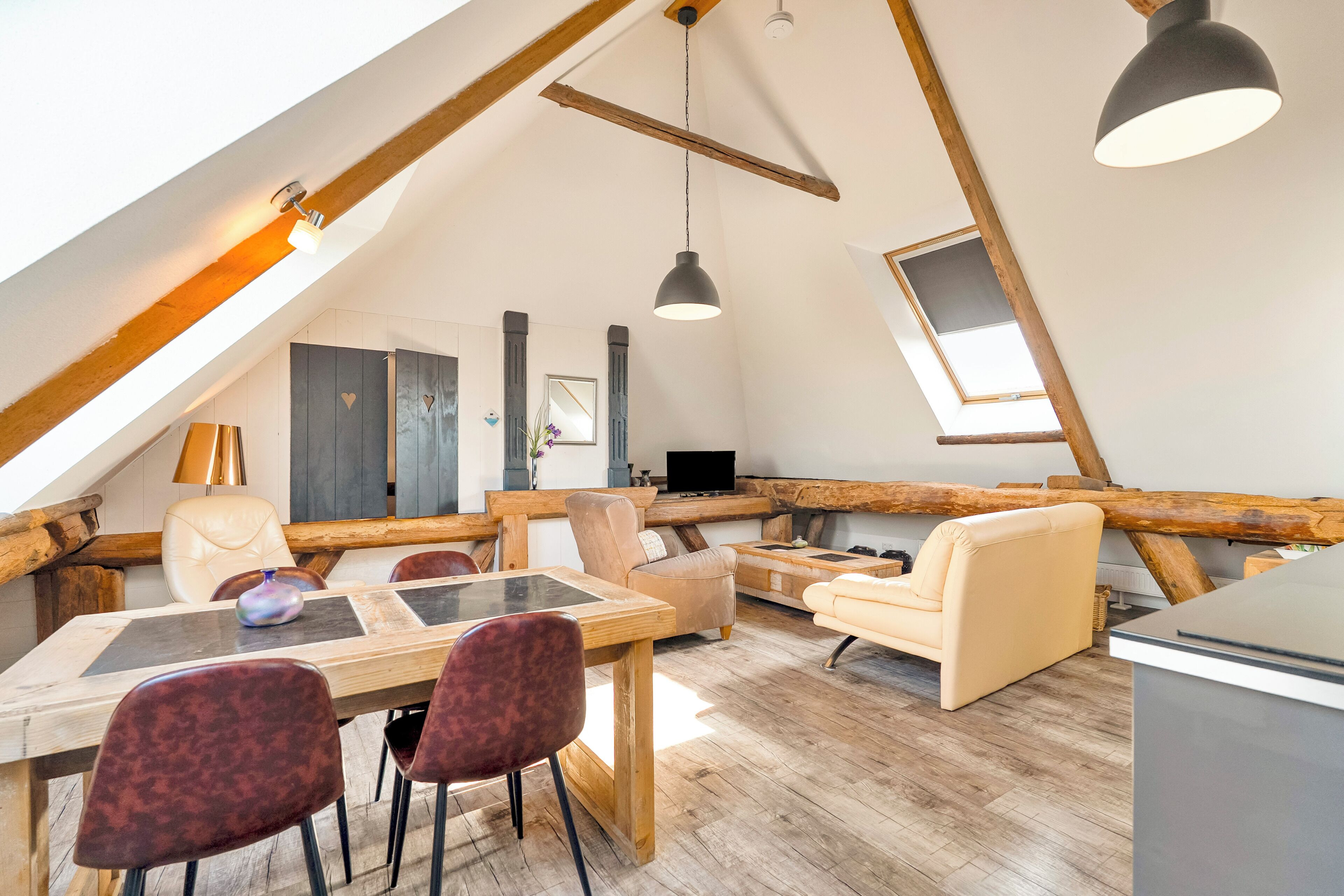 Ein Loft-Zimmer mit Esstisch, Stühlen, einer Couch und einem Fernseher.