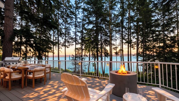 A deck with outdoor furniture, a fire pit, and a view of the ocean.