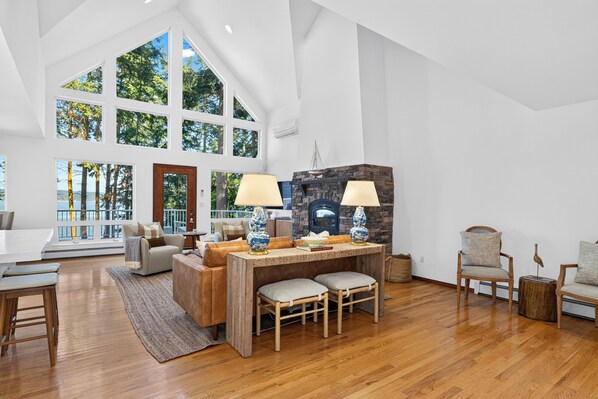 Una habitación amplia con techos altos, ventanas grandes, chimenea y comedor.