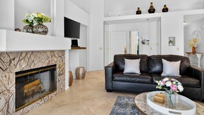 Un salon moderne avec une cheminée, un canapé en cuir et un téléviseur à écran plat.