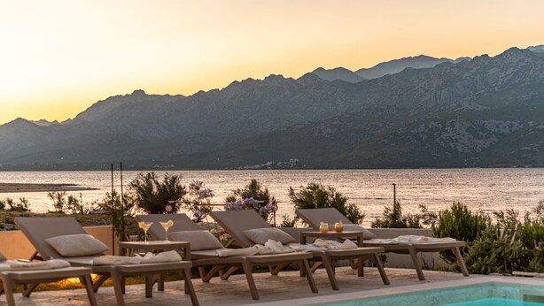 A poolside area with lounge chairs and a view of a lake and mountains. - Villa Wave of Love ZadarVillas (Rovanjska)