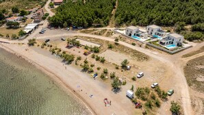 An aerial view of a coastal area with a beach, a pool, and several buildings. - Villa Wave of Love ZadarVillas (Rovanjska)