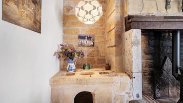 A stone fireplace with a traditional design, a small alcove with a vase of flowers, and a wall-mounted picture.