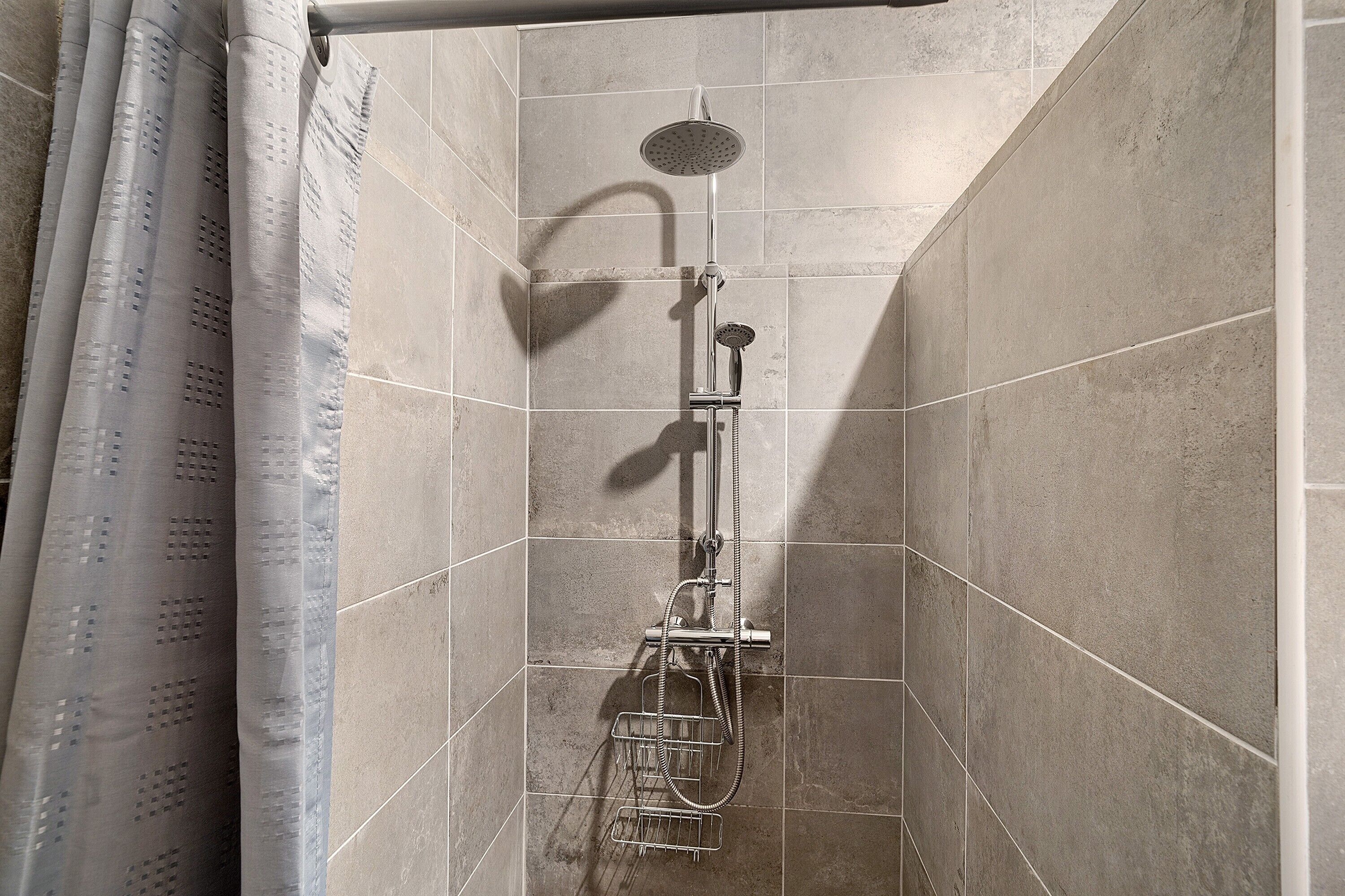 Eine Dusche mit Duschbrause und verstellbarem Wasserhahn.