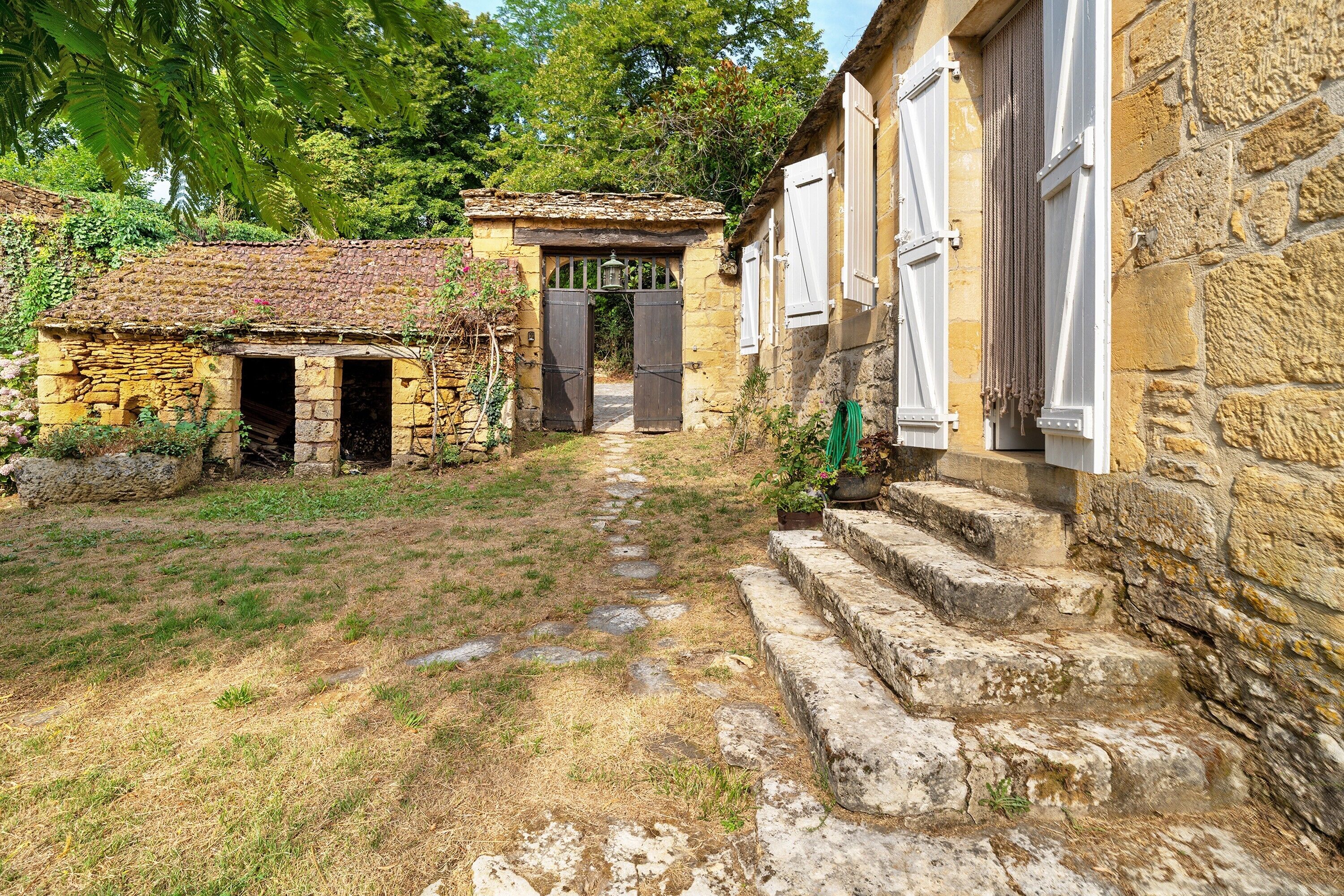 Un bâtiment en pierre, doté d’un toit de chaume et d’un chemin pavé menant à une porte.