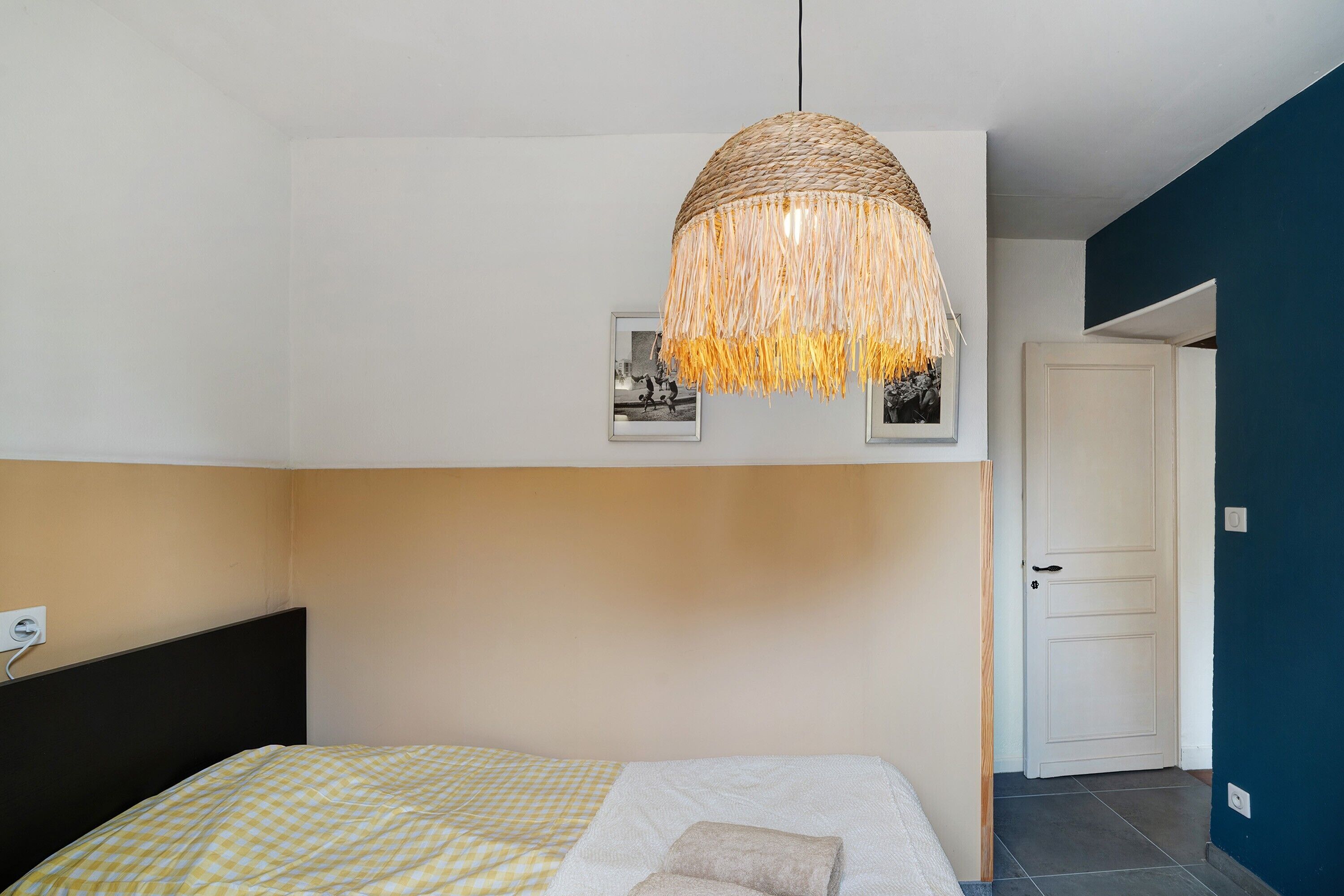 Una camera da letto con un letto, una lampada a sospensione e una porta.