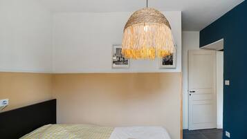 Una camera da letto con un letto, una lampada a sospensione e una porta.