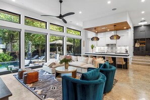 A modern living room with a sofa, chairs, a coffee table, and a view of a pool and garden. - South Austin Retreat • Pool + Fire Pit • Near South Congress | Oaklane Zen (Austin)