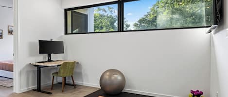 A modern room with a desk, chair, exercise ball, yoga mat, and dumbbells.