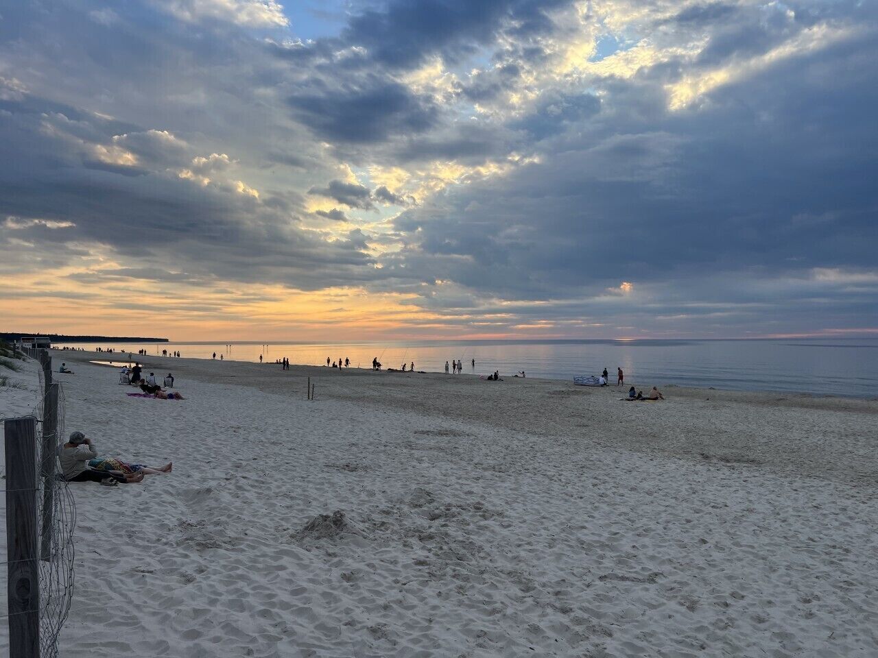 A beach with people relaxing and walking along the shore.