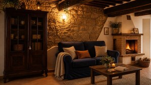 Ein gemütliches Wohnzimmer mit einer Steinwand, einem Kamin, einem dunkelblauen Sofa und einem Holzschrank.