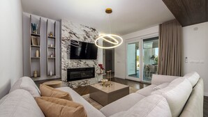 Un soggiorno moderno con un divano, una TV a schermo piatto, un camino e una lampada a soffitto.