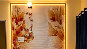 Una habitación de hotel con una cama grande, una lámpara fijada a la pared y un panel decorativo.