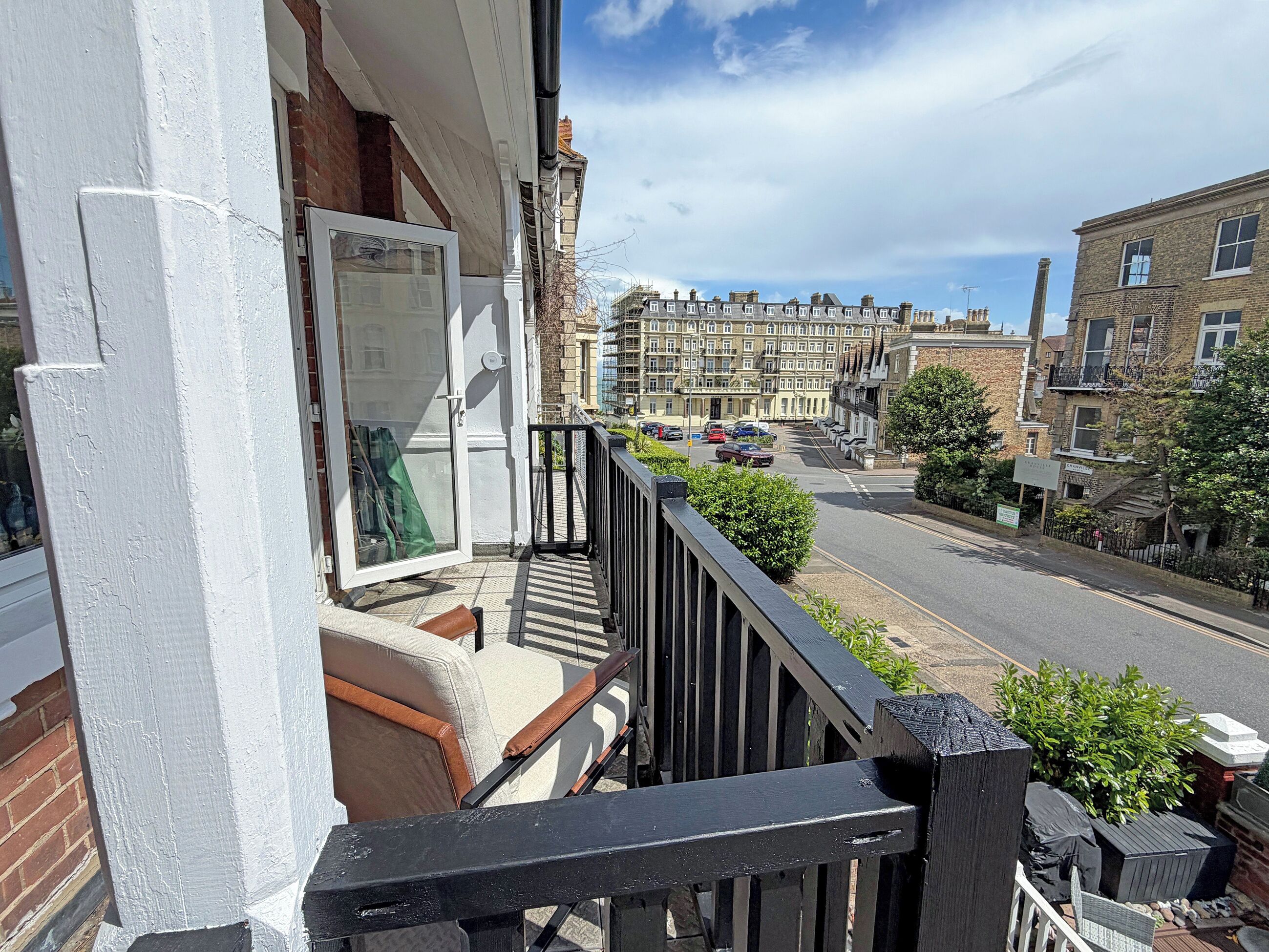 Un balcon donnant sur une rue résidentielle, une porte et une fenêtre.
