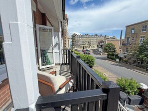 Een balkon met uitzicht op een woonstraat, een deur en een raam.