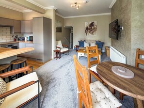Een moderne keuken met een eethoek, houten meubels en een groot schilderij aan de muur.
