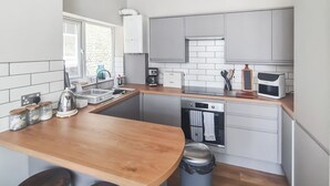 A modern kitchen with a wooden island, built-in appliances, and a window with a view.