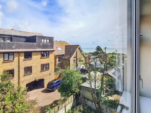 A residential area with brick houses, a blue car, and a view of the sea. - 2 bedroom accommodation in Broadstairs (Broadstairs)