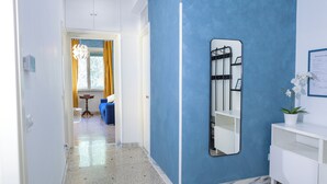 Un pasillo con una pared azul de acento, un tocador blanco con espejo, y un sofá azul al fondo.